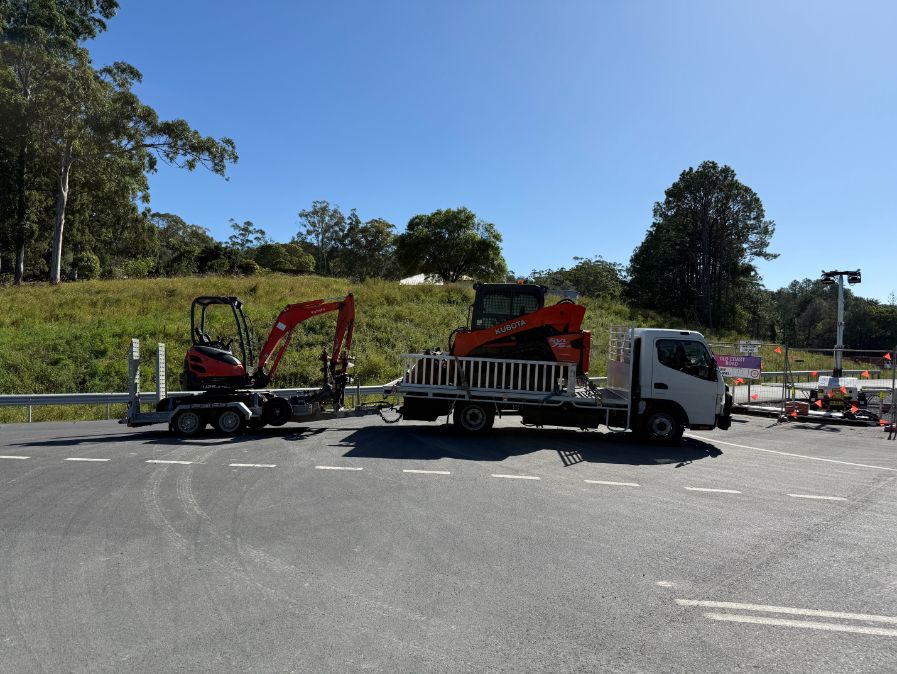A white truck carrying a tractor in the tray and trailer attached behind — Goulburn Transport In Goulburn, NSW