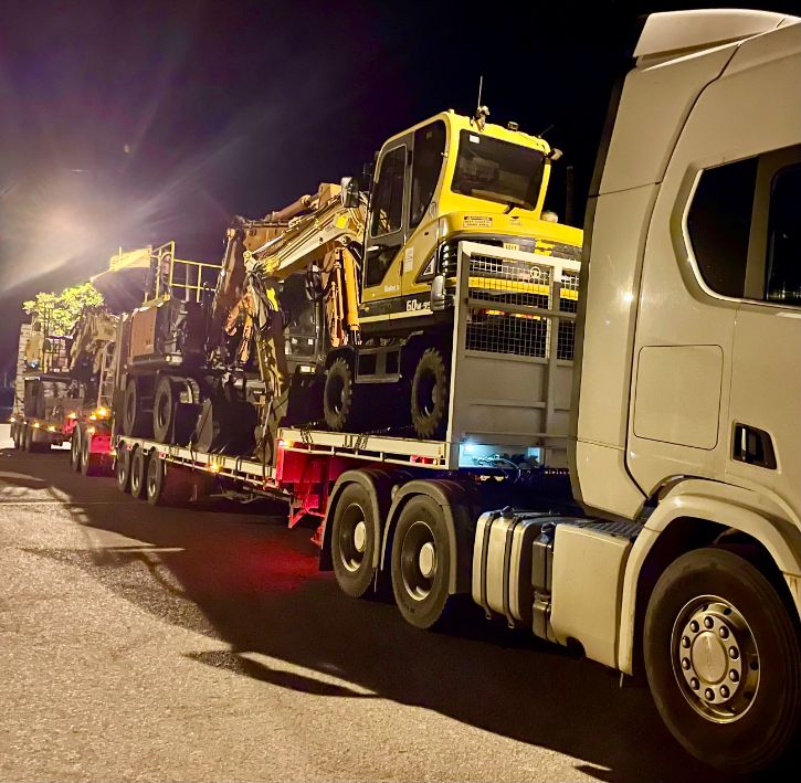 A White Semi Truck is Carrying a Load of Heavy Machinery on a Trailer — Goulburn Transport In Southern Highlands, NSW