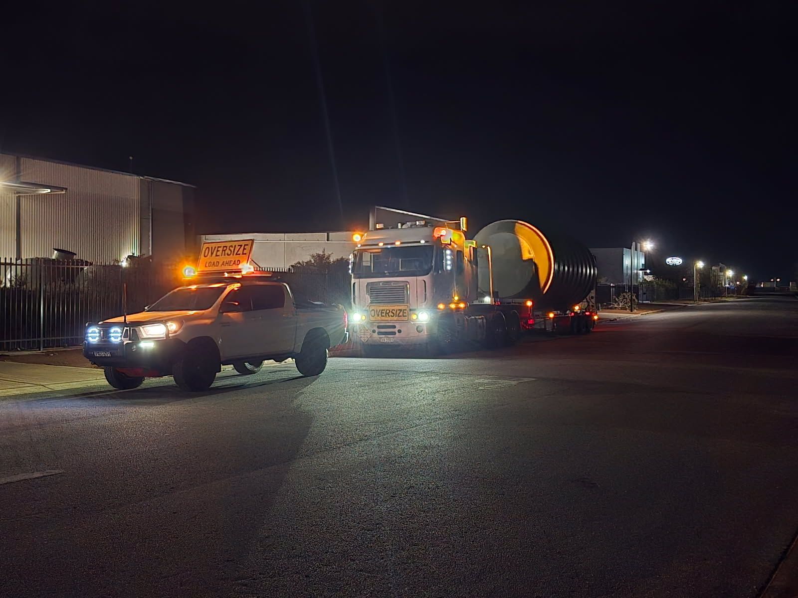 A Ute is leading an oversized truck at night — Goulburn Transport In Goulburn, NSW