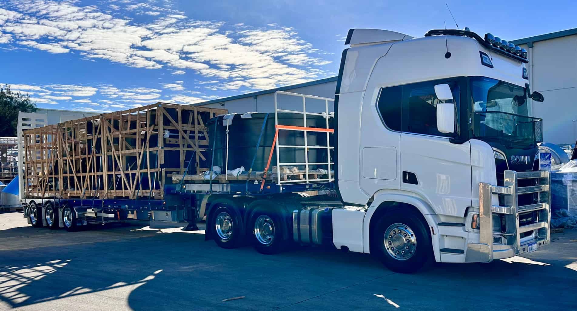 A White Semi Truck is Carrying a Wooden Structure on a Trailer — Goulburn Transport In Goulburn, NSW