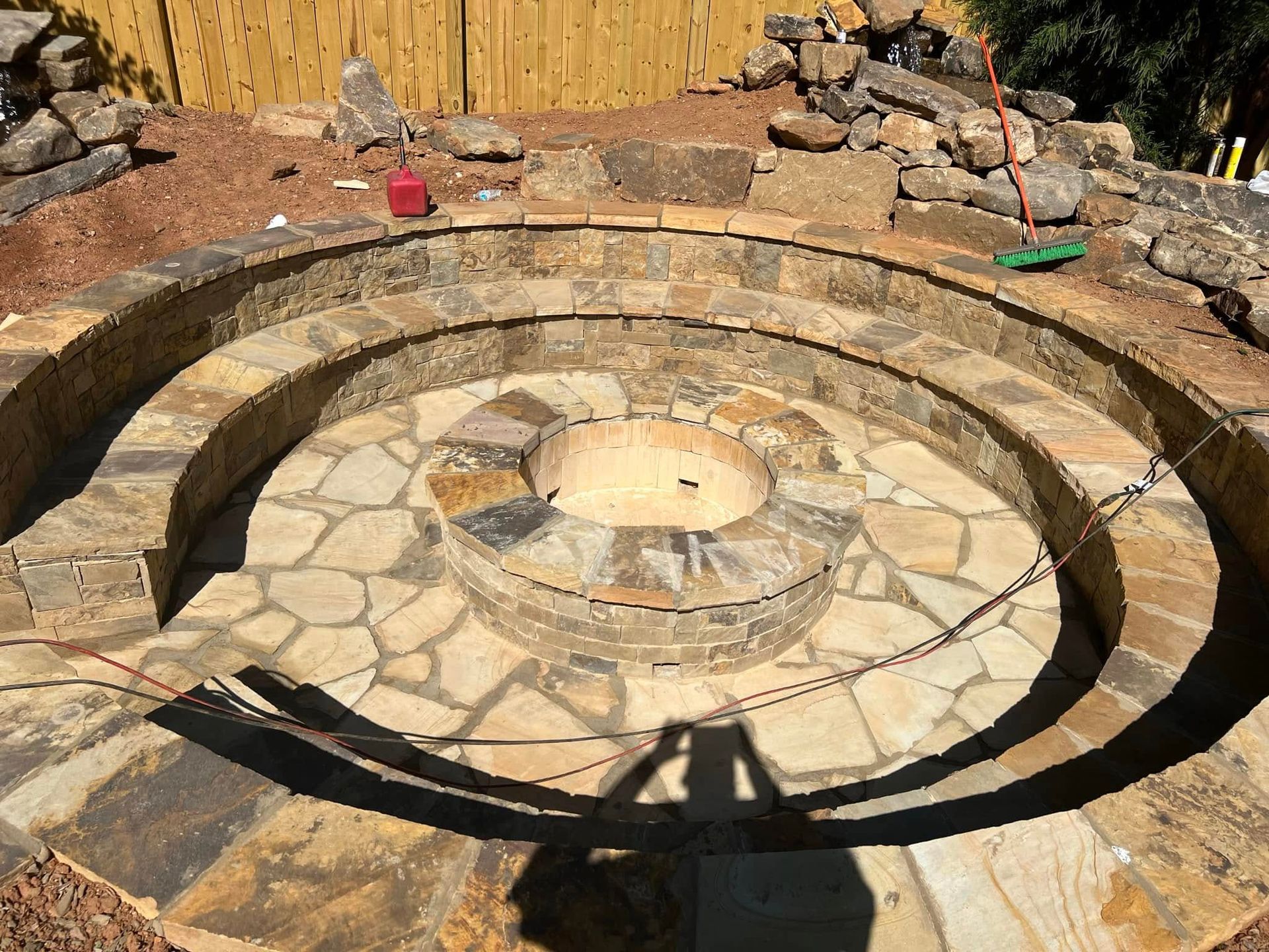 Stone fire pit patio with circular seating wall and flagstone paving in a backyard