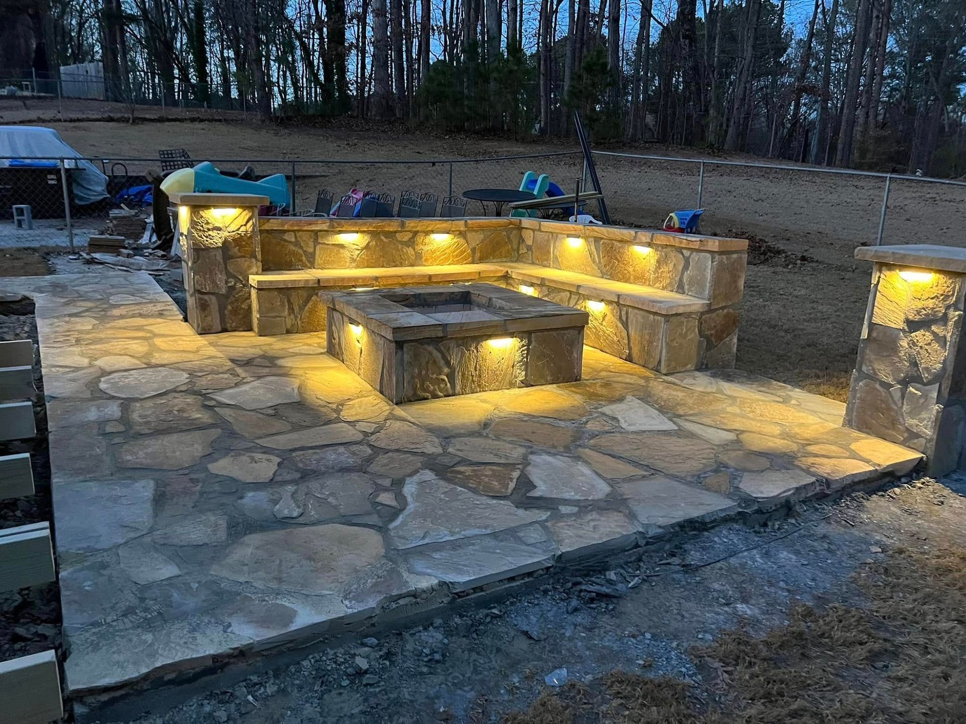 Stone outdoor seating area with built-in benches and warm lights at dusk