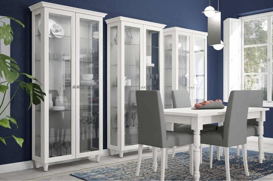 Sala da pranzo luminosa con mobili bianchi, sedie grigie, un tavolo bianco e pareti con accenti blu vicino a grandi finestre.