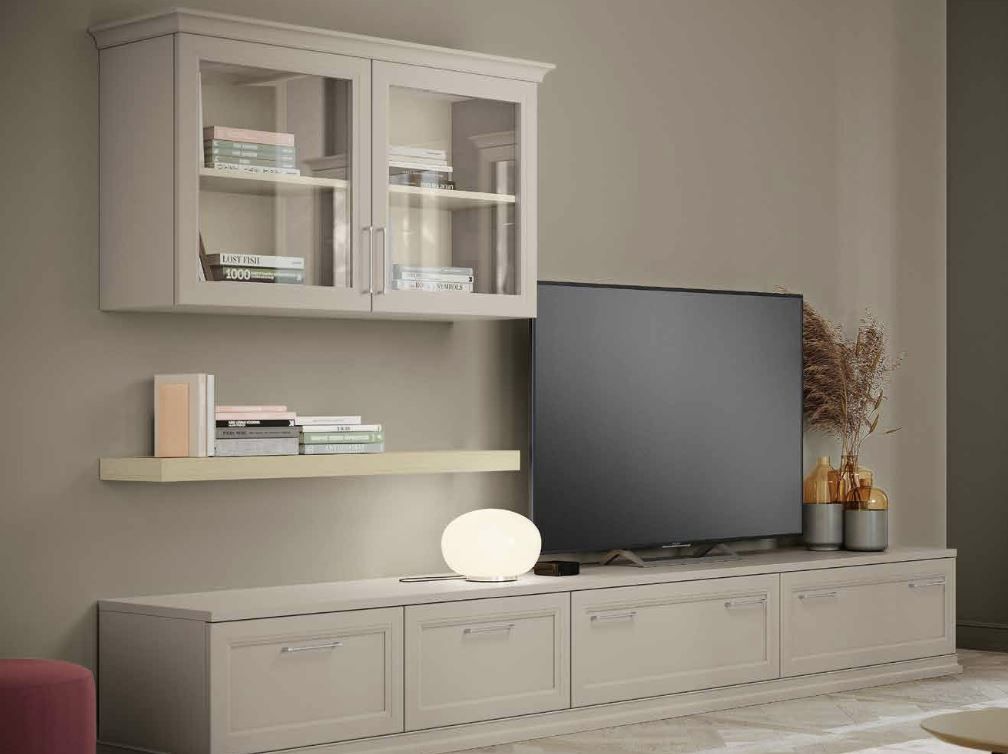 Soggiorno moderno con mobili a incasso beige, mensole a muro, TV e lampada da tavolo dalla luce soffusa.