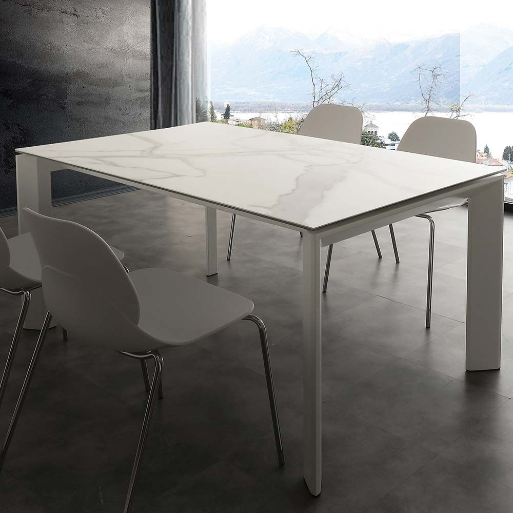 Moderno tavolo da pranzo bianco con sedie in una stanza luminosa con vista su un paesaggio innevato.