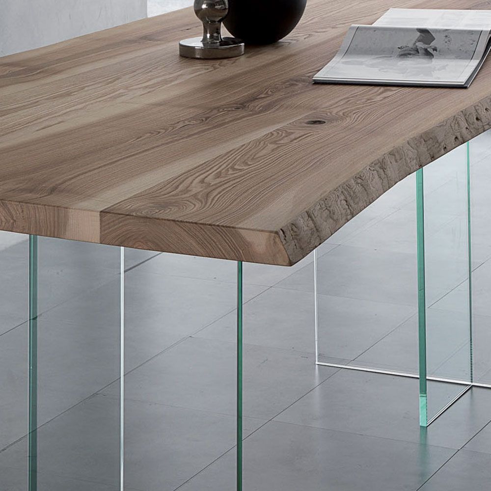 Tavolo moderno in legno con gambe in vetro trasparente in un interno minimalista