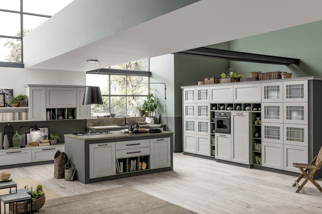 Cucina moderna a pianta aperta con isola grigia, mobili bianchi e un'ampia dispensa a muro in stile rustico.