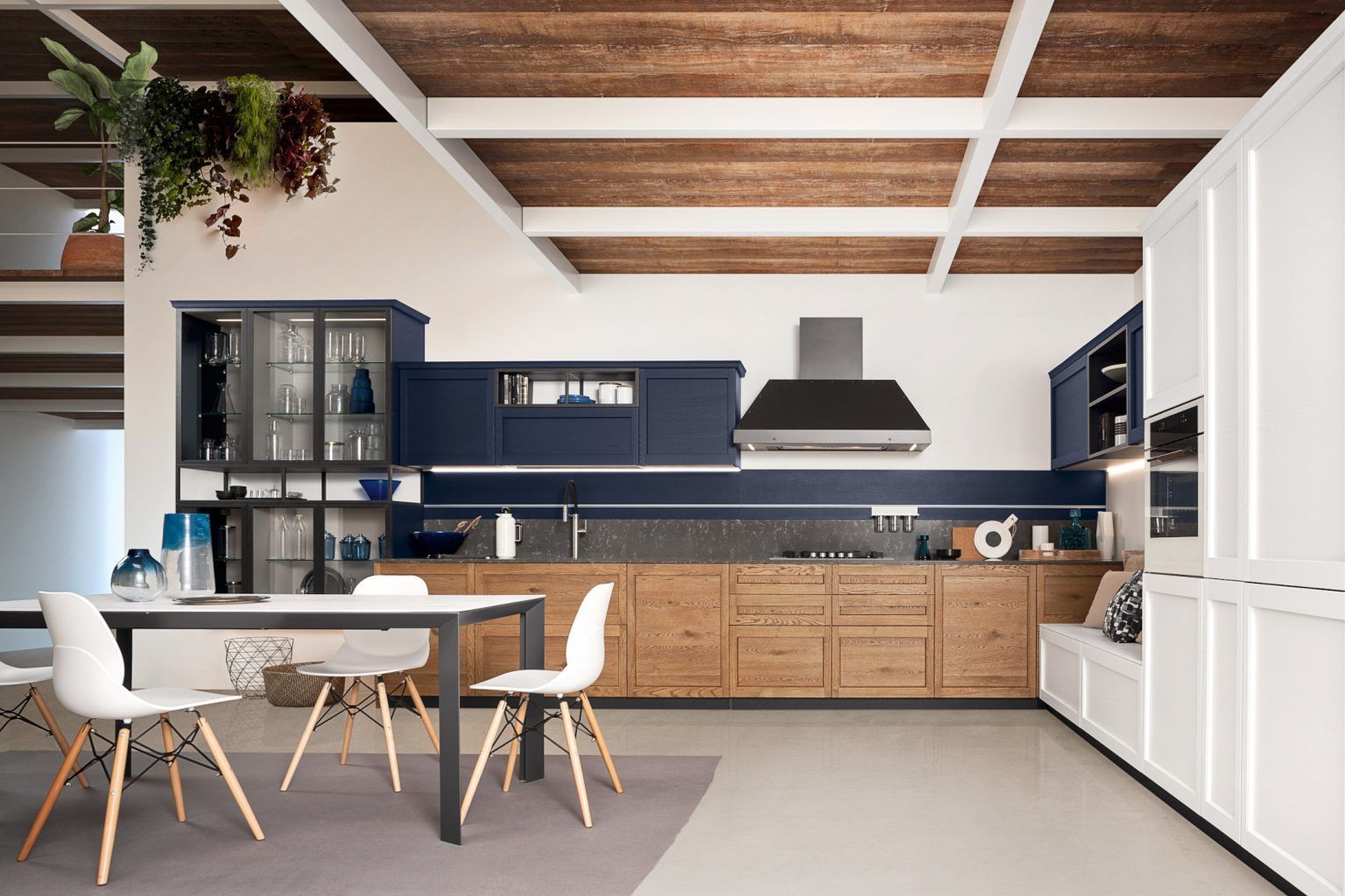 Cucina moderna con soffitto in legno, mobili blu navy, isola centrale bianca e sedie contemporanee.