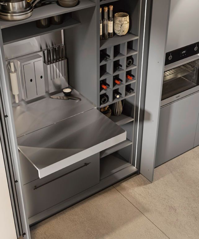 Mobile da cucina grigio con ripiano estraibile, portabottiglie e forno a incasso.