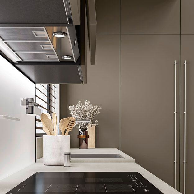 Cucina moderna con piano cottura nero, ripiano di lavoro bianco, utensili e pensili alti color tortora.