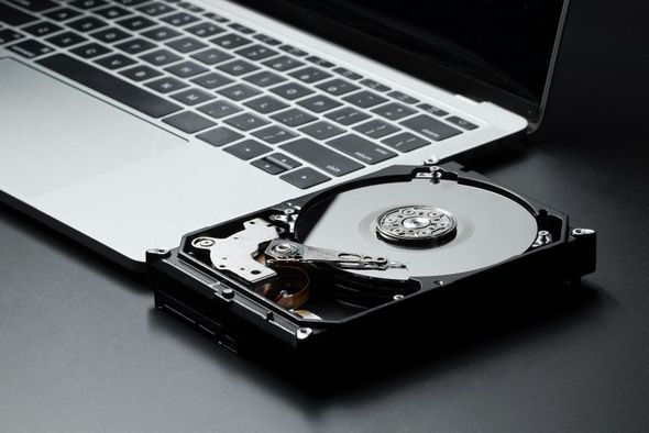 A hard drive is sitting on top of a laptop computer.