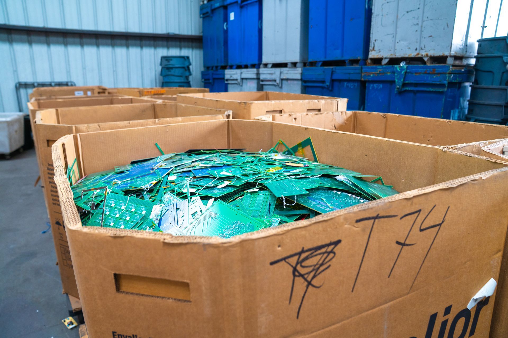 A cardboard box filled with green pieces of plastic and the number t74 written on it