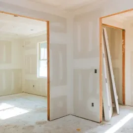 Interior of a room under construction, with drywall, unfinished doorways, and a window.