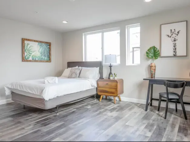 A bedroom with a bed , nightstand , desk and chair.