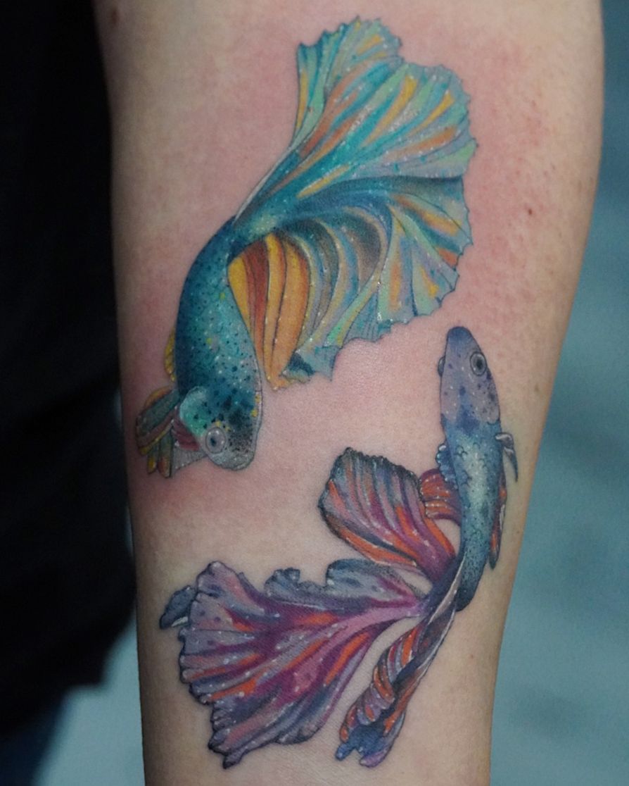 A person has a tattoo of two fish on their arm.