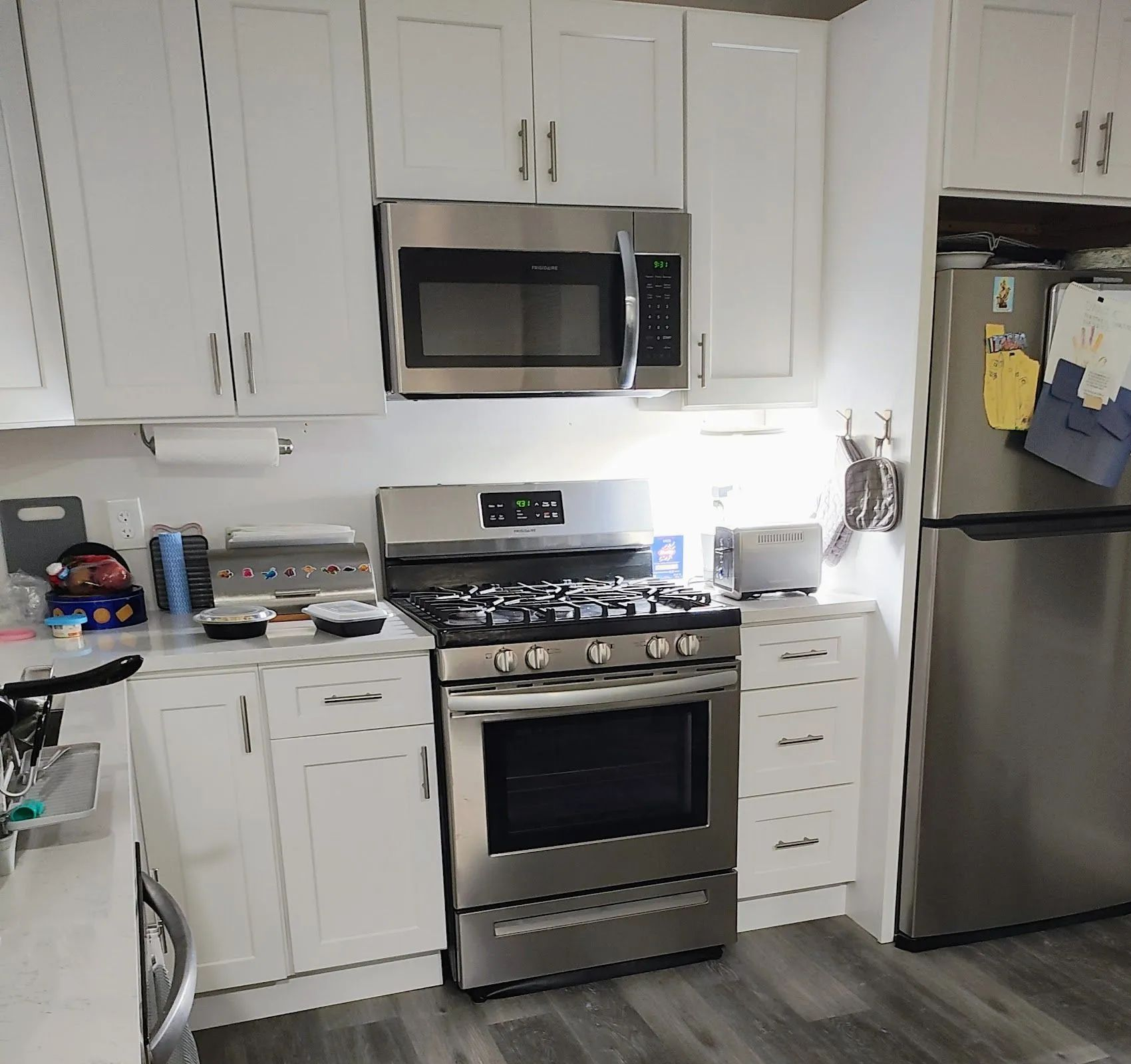 Bright kitchen with white cabinets, stainless steel appliances, and a gas stove centered between counters.