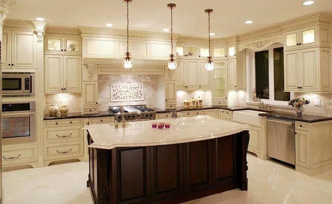 Elegant cream-colored kitchen with large central island, pendant lights, and stainless steel appliances