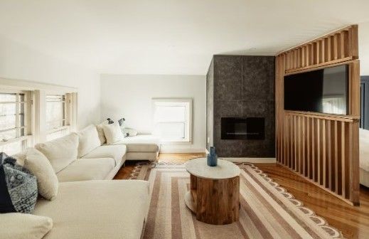 Modern living room with white sectional, wood-accent TV wall, and striped rug