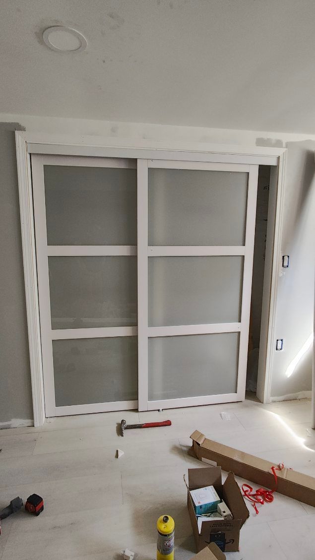 Painted white built-in closet or wall cabinet under construction, with tools and materials on a floor covered in dust.