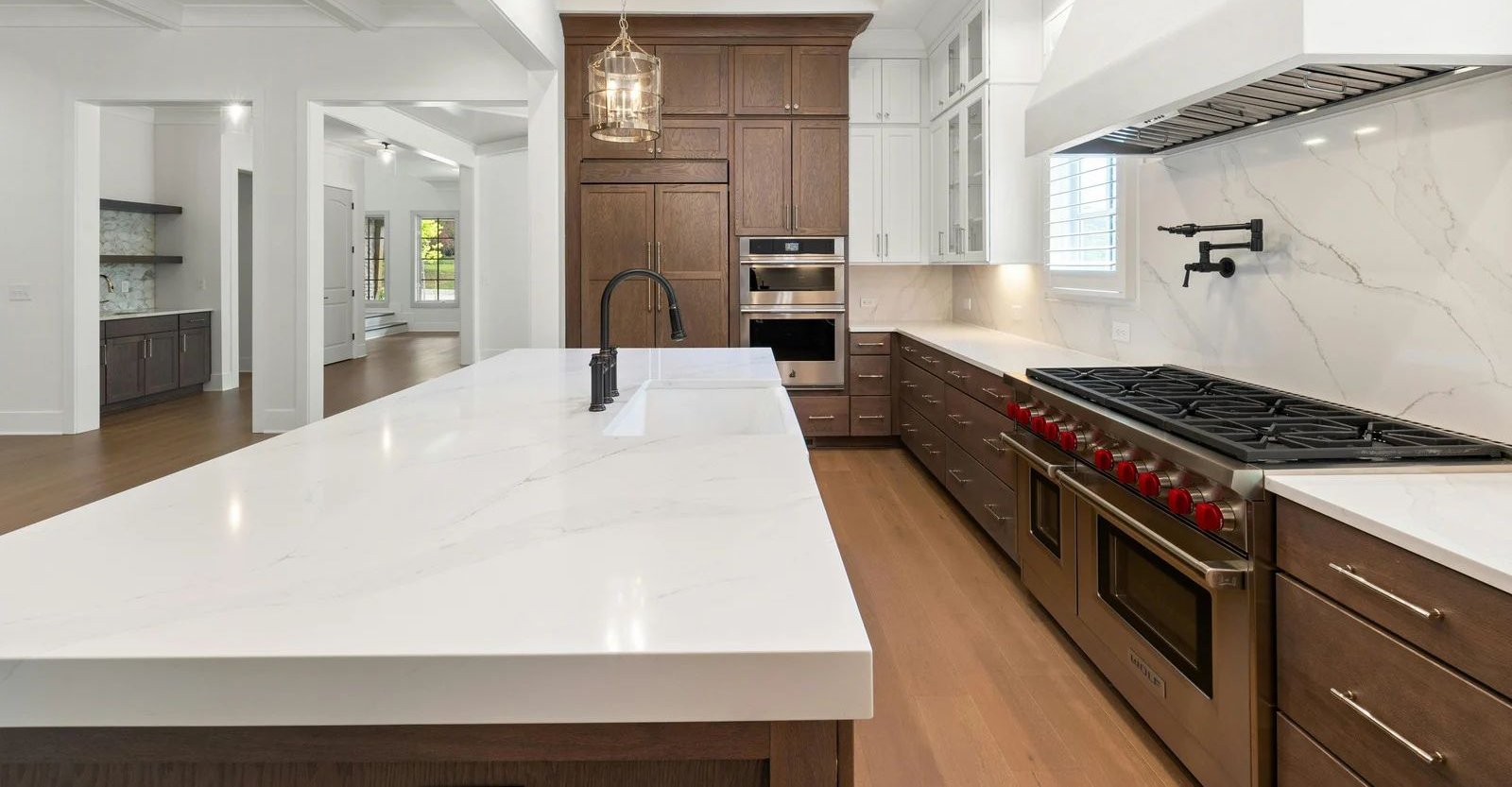 Modern kitchen with large white island, dark cabinets, stainless appliances, and wood floors