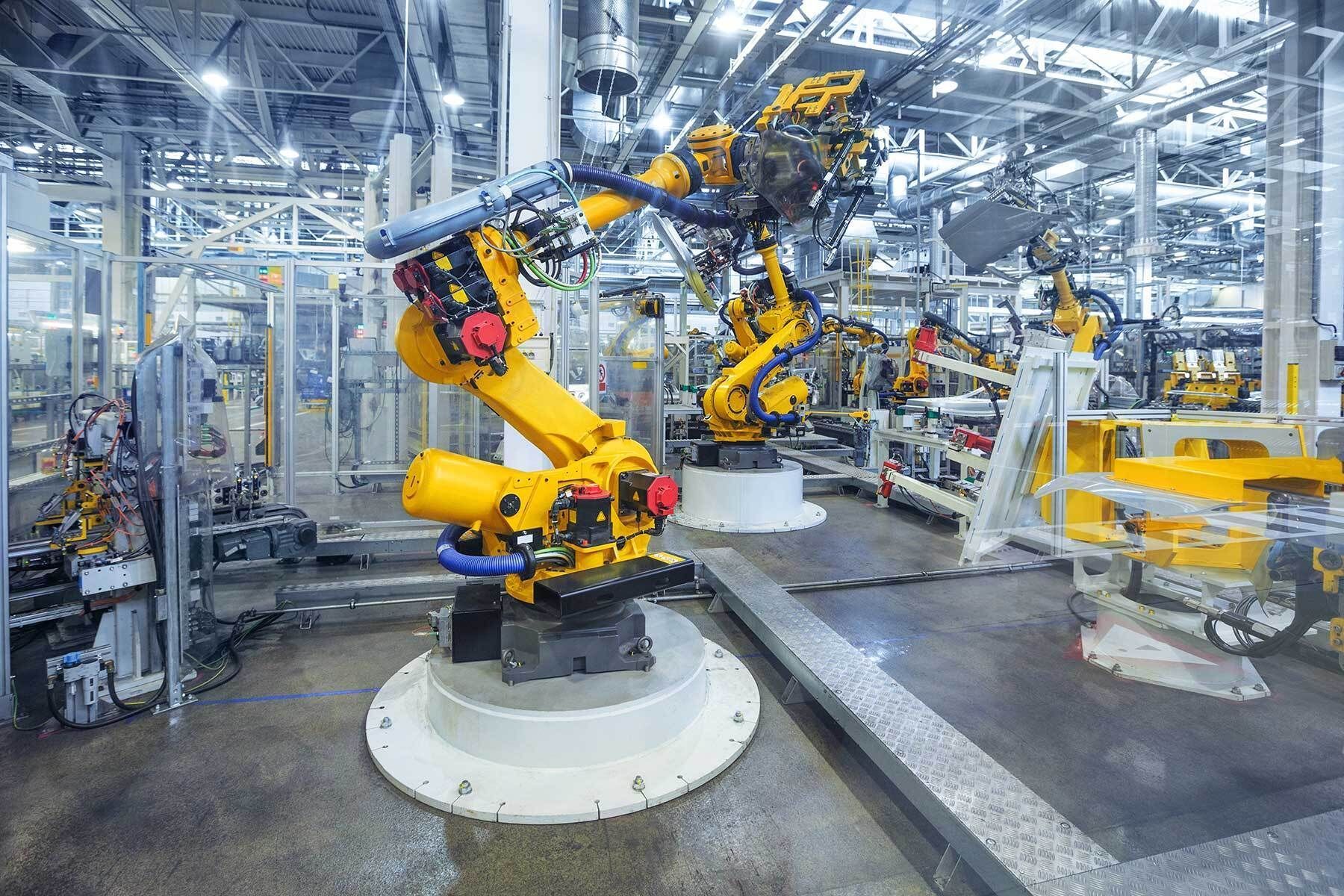 Robotic arms assembling parts on a factory line in a bright automated manufacturing plant