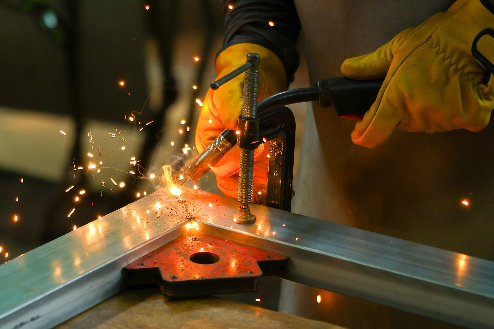 Worker welding metal beams with bright sparks flying