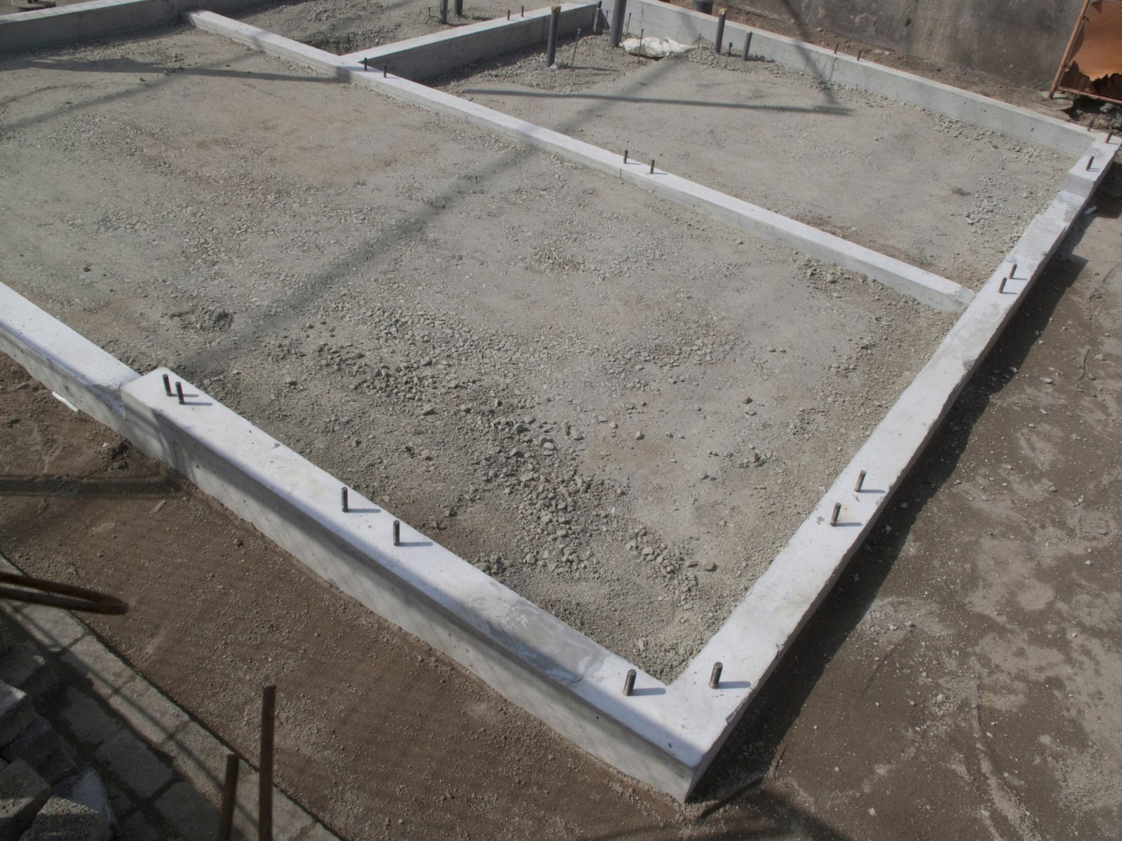 Concrete foundation framework with embedded metal anchors, ready for construction.