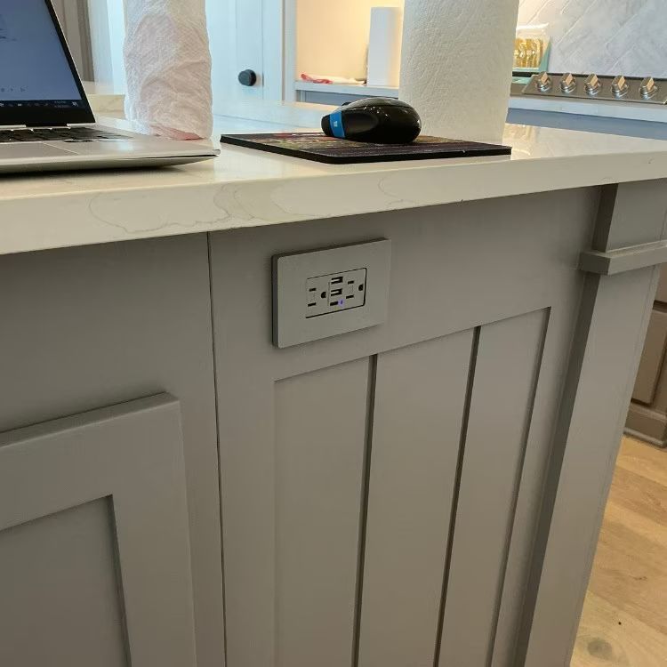 Kitchen island with laptop and mouse, plus a built-in electrical outlet on the front panel