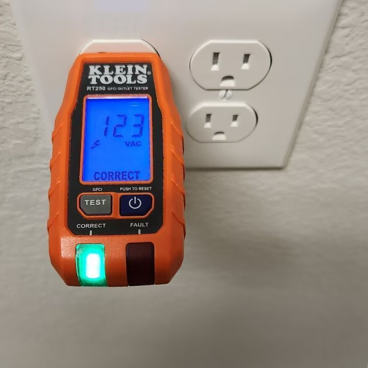 Klein Tools outlet tester plugged into a white wall outlet, showing 123 V and CORRECT.