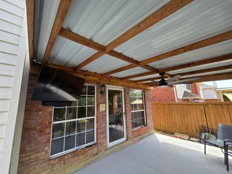 Covered brick patio with corrugated roof, French doors, window, ceiling fan, TV, and seating area