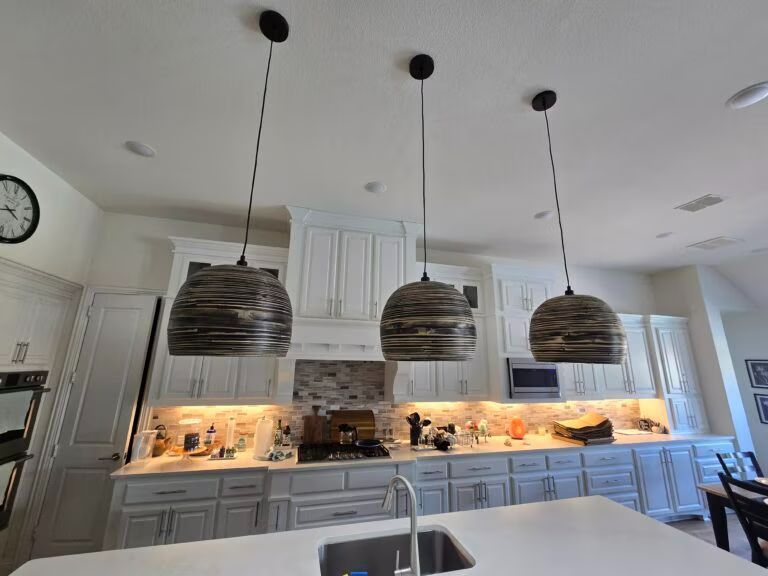 Modern white kitchen with pendant lights, marble island, and illuminated backsplash counter
