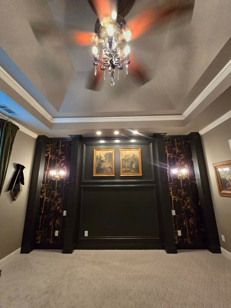Elegant dark home theater with chandelier, wall sconces, framed art, and a large blank screen area