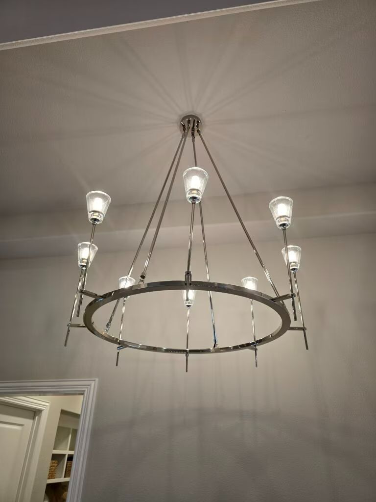 Modern circular chandelier with lit bulbs hanging from a ceiling in a room