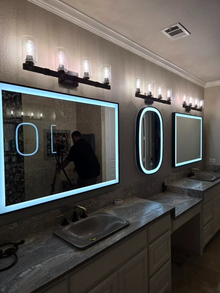 Elegant restroom with lit mirrors above sinks and countertops, viewed from a doorway