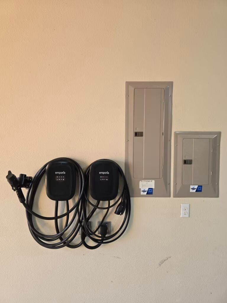 Wall-mounted EV charging stations and electrical panels on a beige wall.