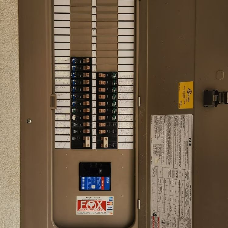 Electrical breaker panel with rows of circuit breakers and a small display in a beige utility closet.