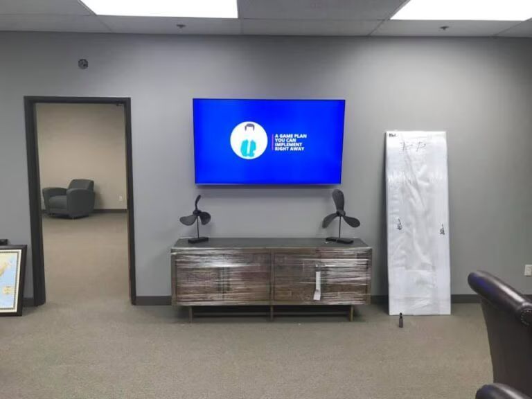Wall-mounted TV above a wood console in a gray room, with a white panel on the right.