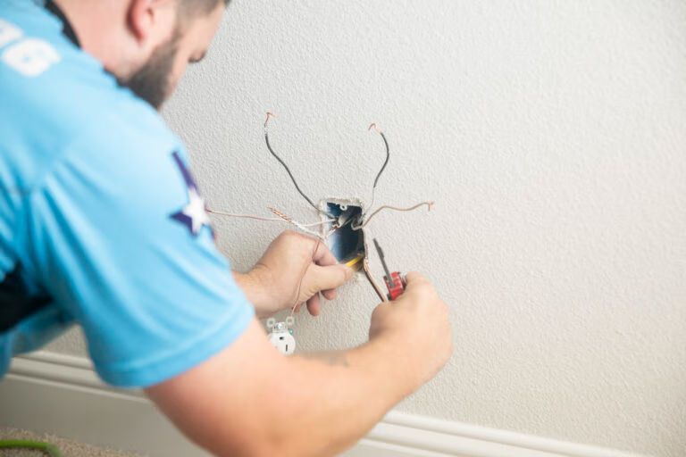 Electrician repairing exposed wall wiring with tools