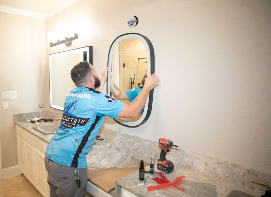 Technician installing a round mirror above a granite bathroom vanity with tools on the counter