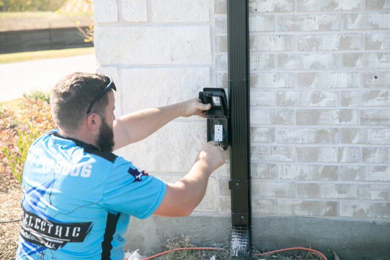 Worker installing a black wall-mounted device on a brick house exterior
