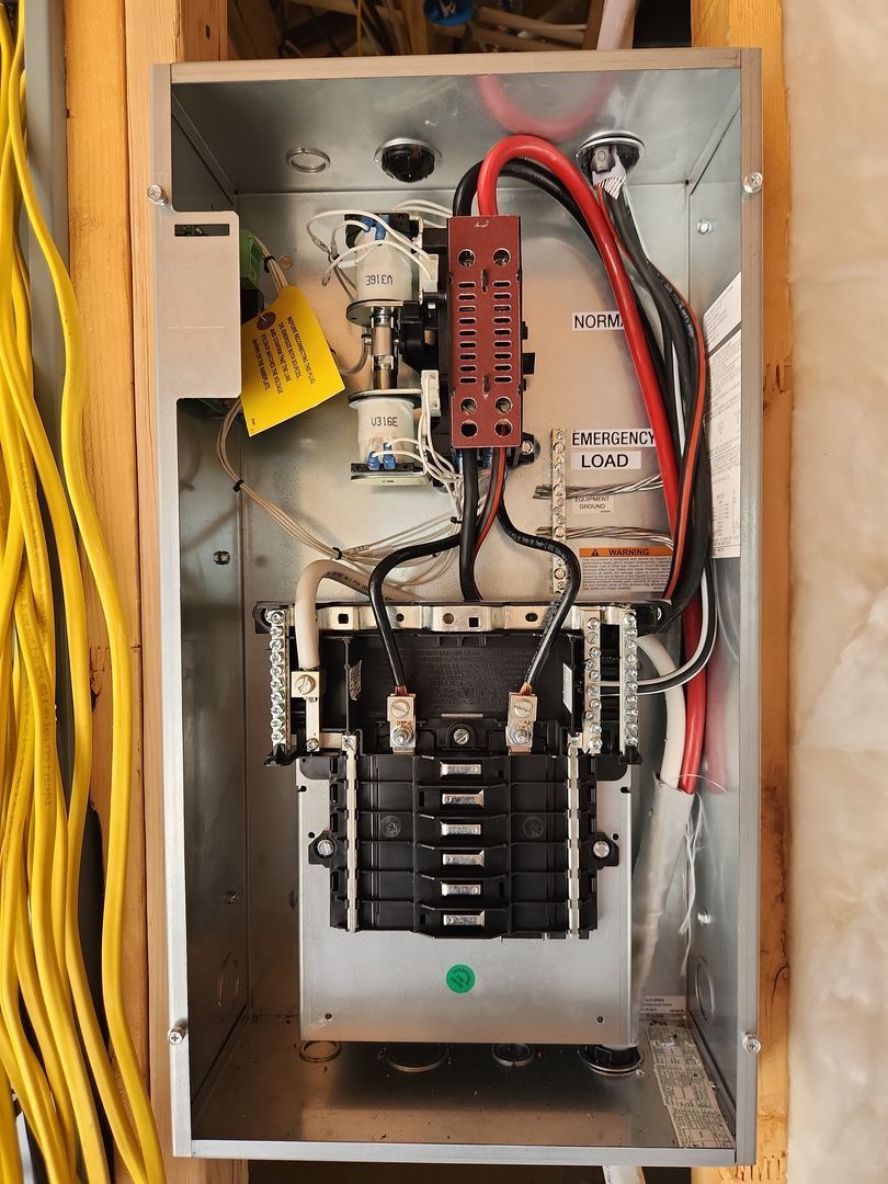 Open electrical breaker panel with red and black cables inside a metal enclosure.