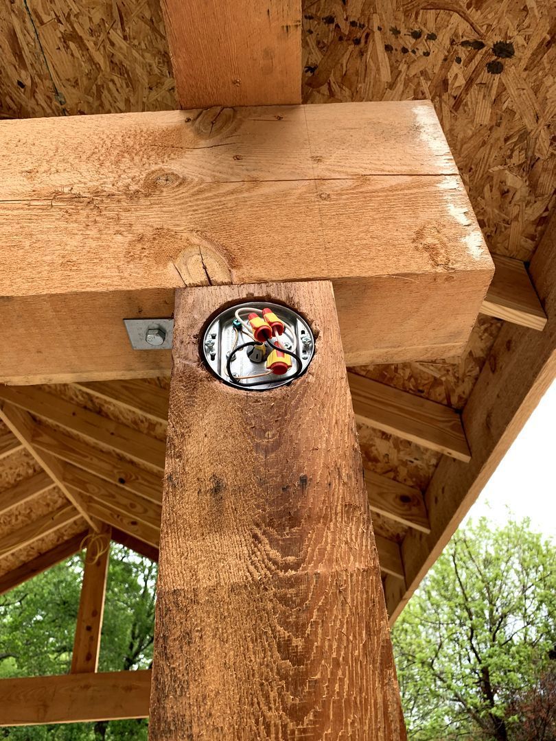 Wooden pavilion beam with a small circular sticker mounted beneath the roof