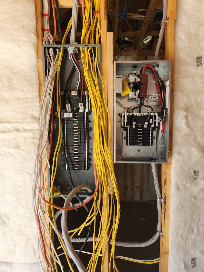 Open electrical panel with tangled yellow network cables and wiring inside a wall cavity