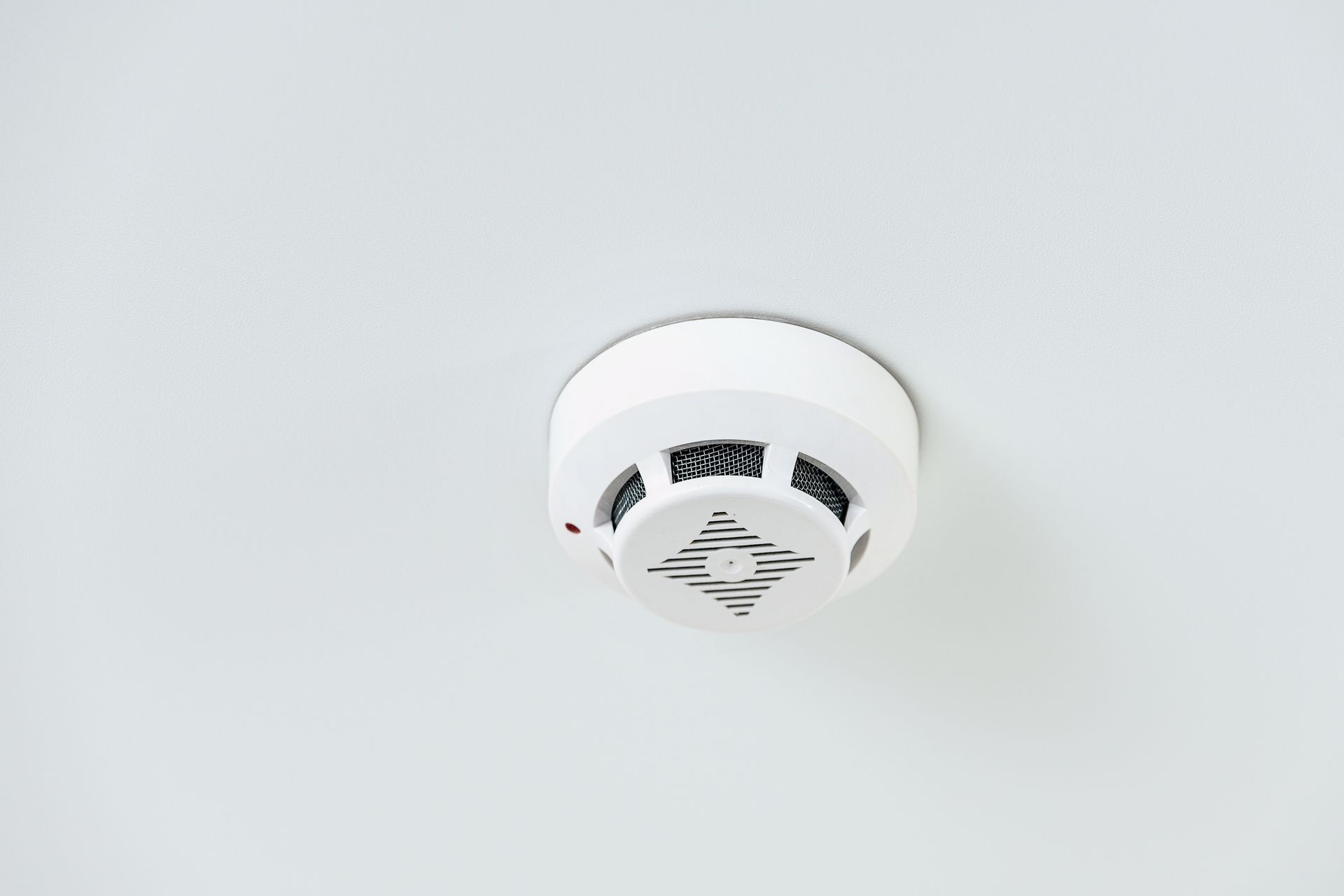 White ceiling smoke detector on a plain white ceiling