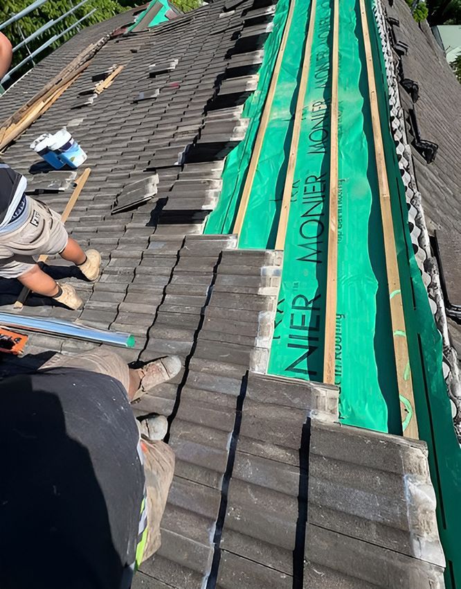 A Man is Working on the Roof of a House — Boss Roof Tiling and Restoration in Caboolture, QLD