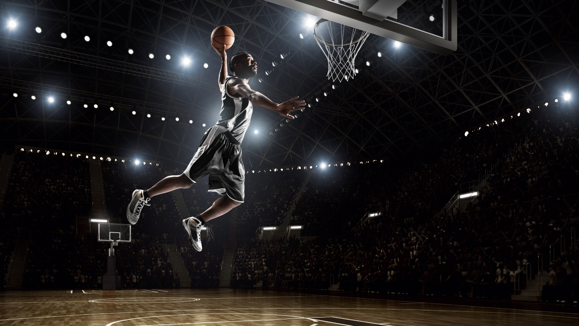 A basketball player is jumping in the air to dunk the ball
