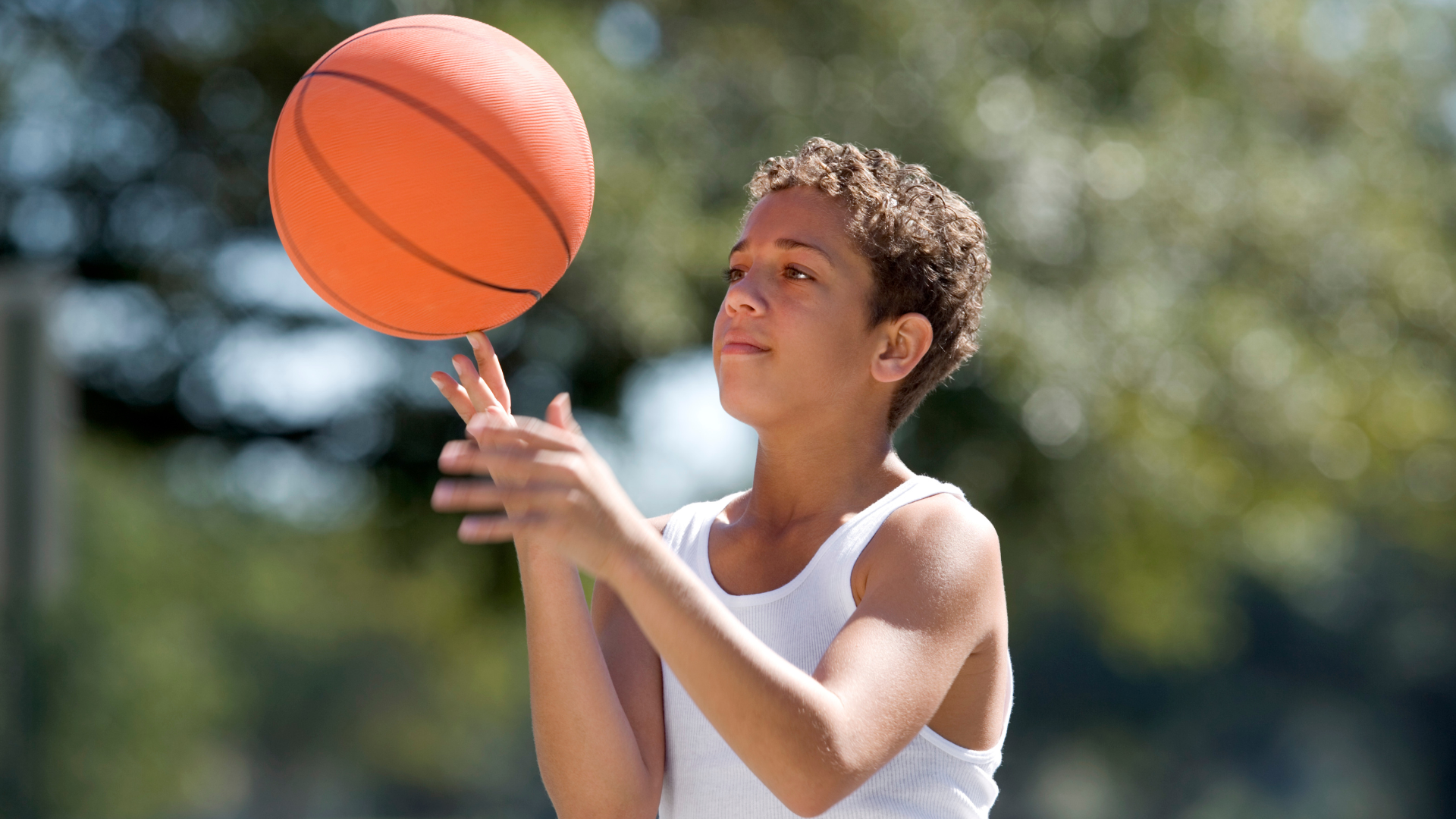 A young boy is throwing a basketball in the air.