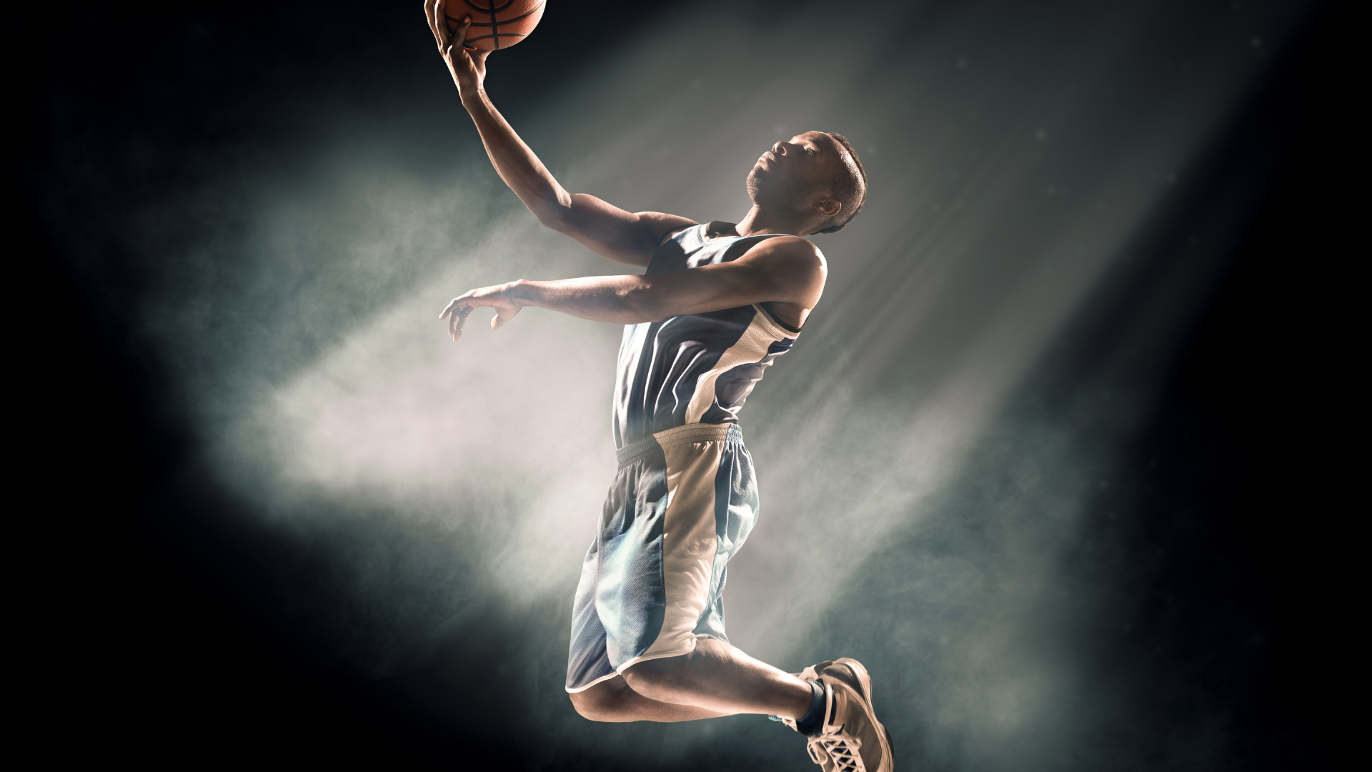 A basketball player is jumping in the air while holding a basketball.