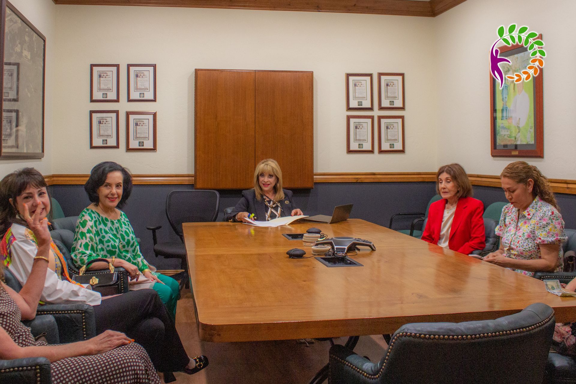 Un grupo de mujeres está sentada alrededor de una mesa en una sala de conferencias.