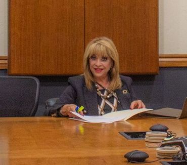 Una mujer está sentada en una mesa de conferencias sosteniendo un trozo de papel.